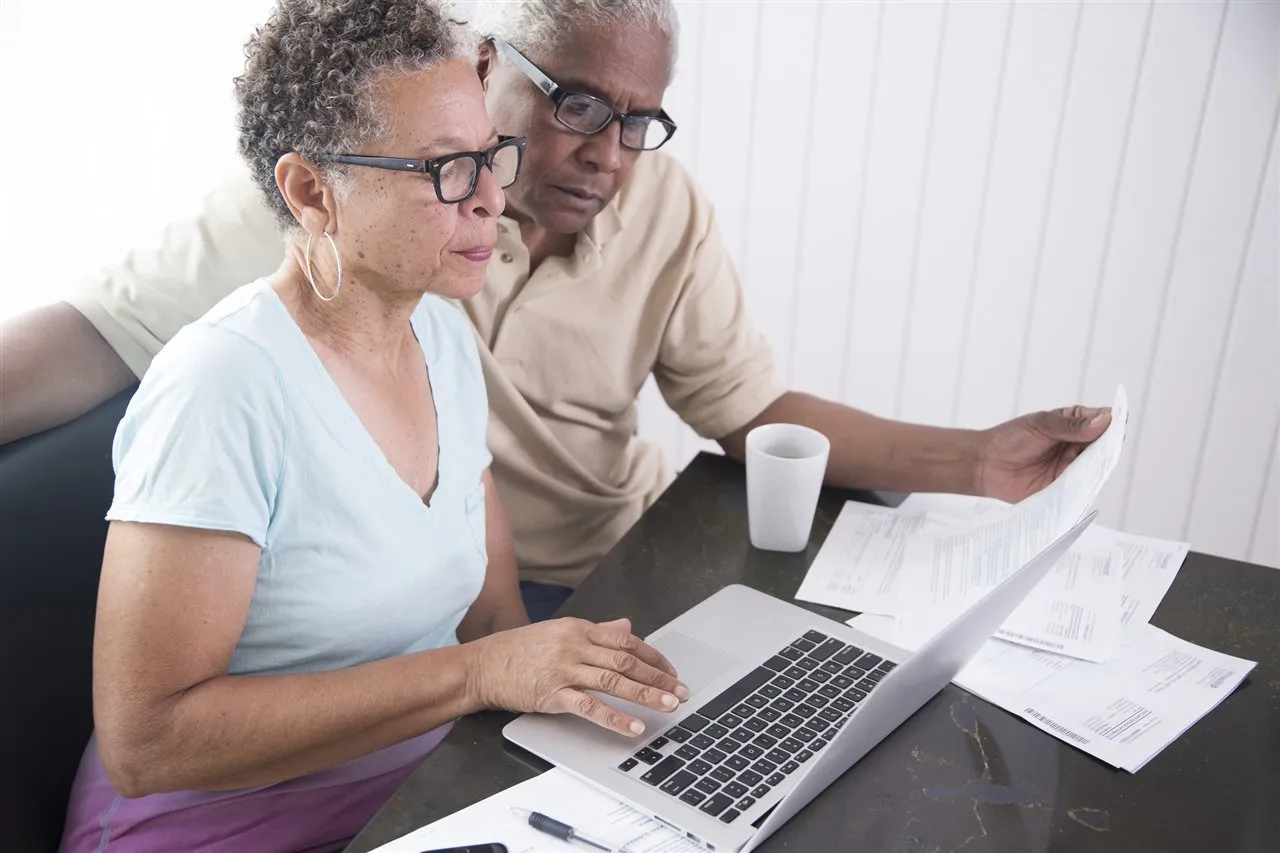 An older couple reviewing plan documents together at a laptop